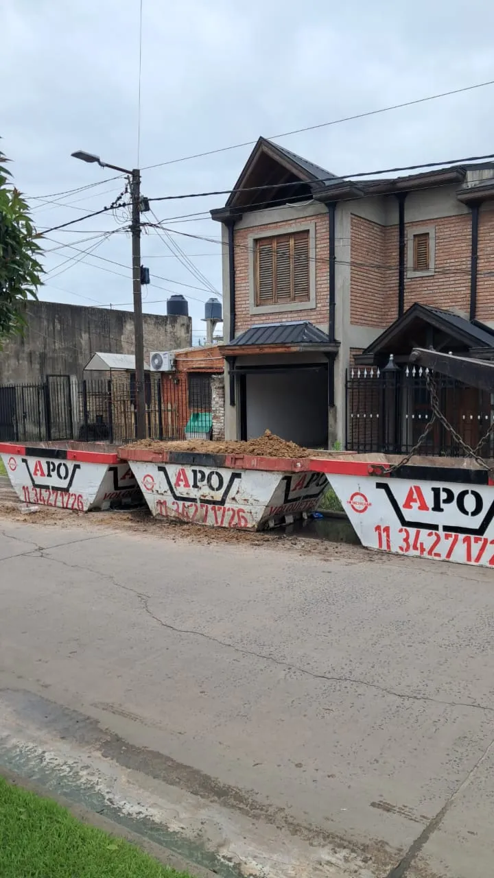 Tres volquetes APO en la calle frente a una casa